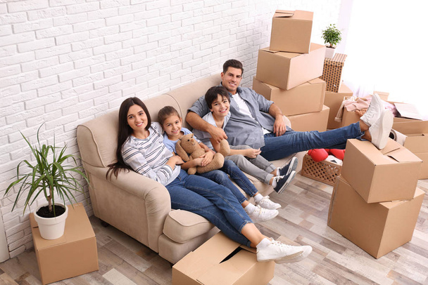 Happy family resting in room with cardboard boxes on moving day - Fotoğraf, Görsel