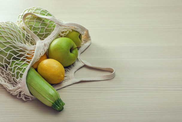 Net bag with vegetables and fruits on wooden table. Space for te - Fotografie, Obrázek
