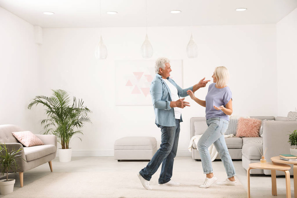 Happy mature couple dancing together in living room - 写真・画像