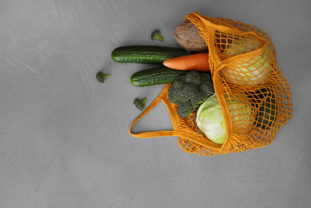 ライトグレーのテーブルの上に野菜とネットバッグ、フラットレイアウト。空間 - 写真・画像