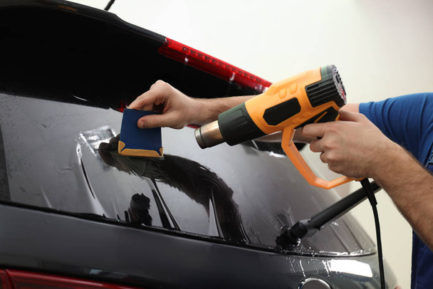 Worker tinting car window with heat gun in workshop, closeup - Foto, Imagen