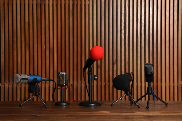 Набор различных микрофонов на деревянном столе. Оборудование для журналистов
 - Фото, изображение