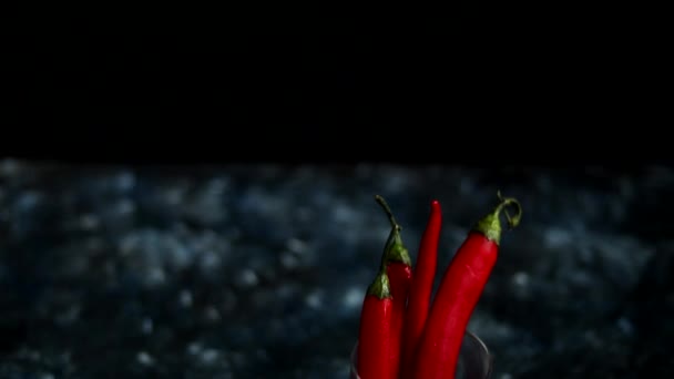 Bright red chili peppers in a transparent glass on a dark blue background. Color Trend - Footage, Video