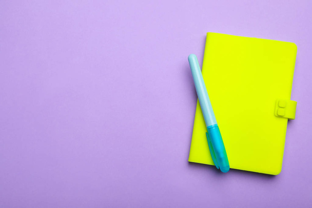 Quaderno verde e pennarello su sfondo lilla, vista dall'alto. Spazio per testo
 - Foto, immagini