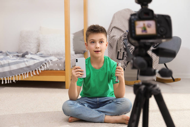 Cute little blogger with phone and selfie stick recording video at home - Foto, afbeelding