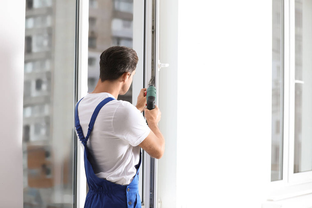 Construction worker repairing plastic window with screwdriver indoors - Foto, Imagem