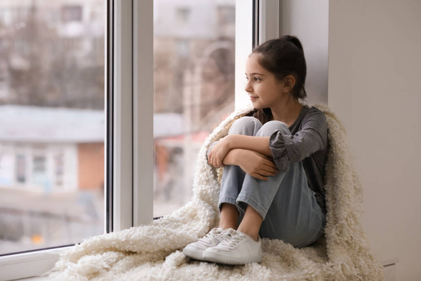 Cute little girl resting near window at home. Space for text - Foto, Imagen