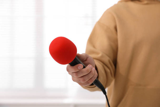 Professional journalist with microphone in room, closeup - Foto, Bild