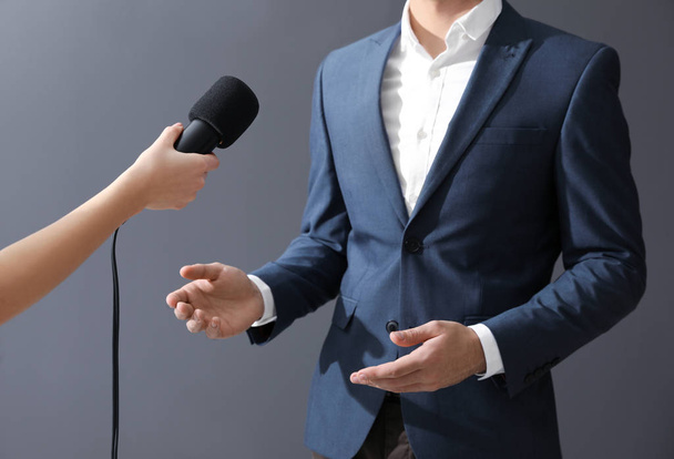 Professional journalist interviewing businessman on grey background, closeup - Foto, immagini