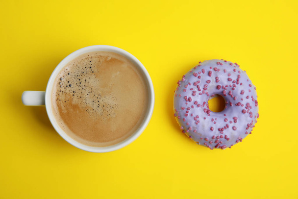Delicious coffee and donut on yellow background, flat lay. Sweet pastries - 写真・画像