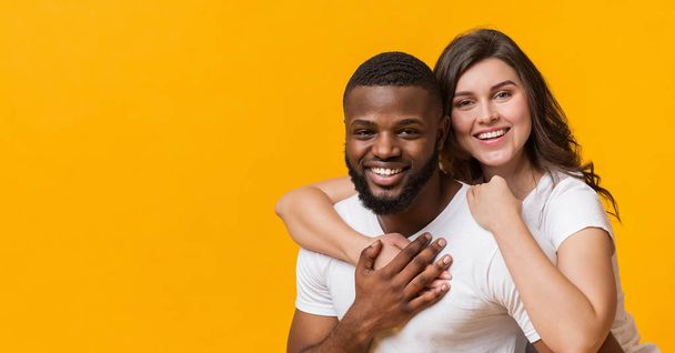 Portrait de couple interracial heureux étreignant et souriant à la caméra
 - Photo, image