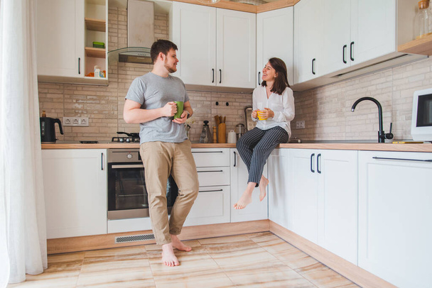 smiling man with woman at kitchen drinking tea - Foto, imagen
