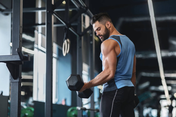 Handsome athlete training arms with dumbbells at gym - Photo, Image