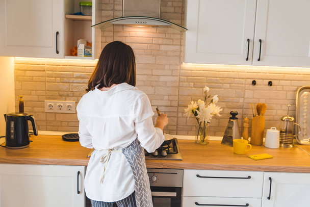view from behind woman on kitchen cooking - Foto, Bild