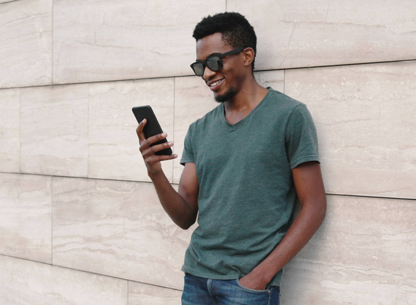 Portrait smiling african man with phone wearing t-shirt, sunglas - Foto, immagini