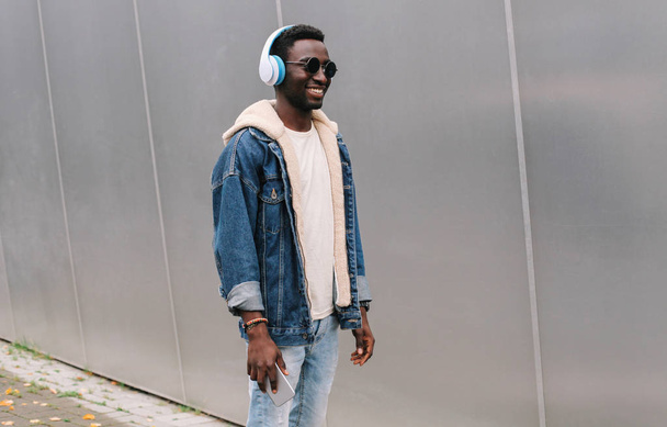 Cool modern smiling african man in wireless headphones listening - 写真・画像
