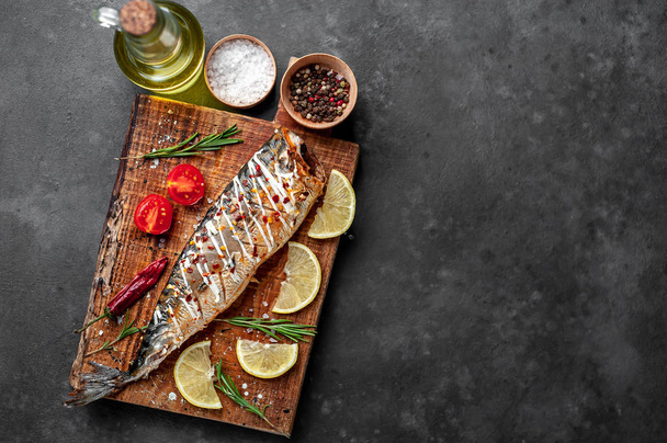 Baked mackerel with lemon, tomatoes and rosemary served on wooden board - Valokuva, kuva