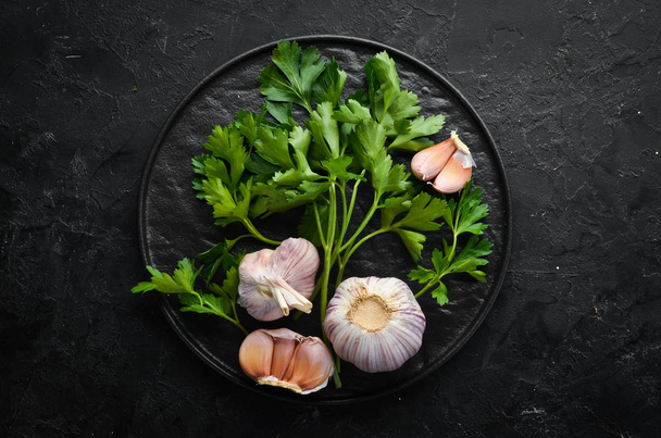 Fresh parsley and garlic on a dark background. Vegetables. Top view. Free space for your text. - Fotoğraf, Görsel