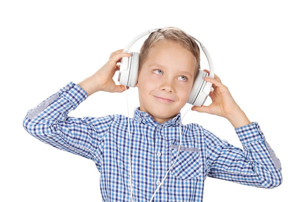 Мальчик слушает музыку в наушниках. Изолированный на белом фоне - Фото, изображение