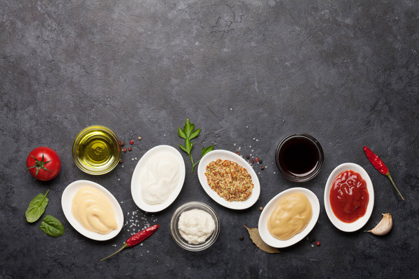 Set of various sauces. Popular sauces in bowls - ketchup, mustard, mayonnaise on dark stone table. Top view with copy space. Flat lay - Photo, Image
