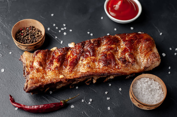 Whole roasted pork ribs on granite table with spices and bbq sauce - Fotografie, Obrázek