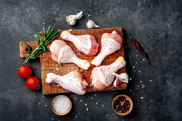 Raw chicken legs served with tomatoes and spices ready for cooking - Foto, immagini