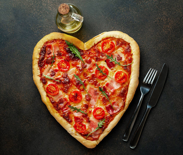 Srdeční pizza s olivovým olejem, vidličkou a nožem na šedém kamenném pozadí. Valentines day concept. - Fotografie, Obrázek