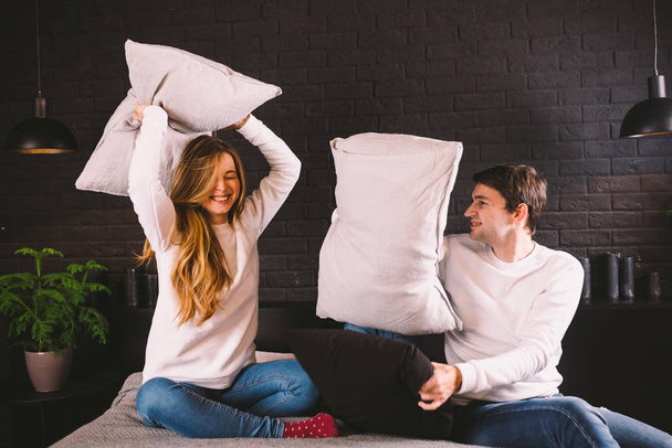 parents with smiling child playing pillow fight on bed, happy family having fun in bedroom, enjoying leisure activity, funny weekend lifestyle. Happy family having fun in bedroom, pillow battle - Foto, Bild