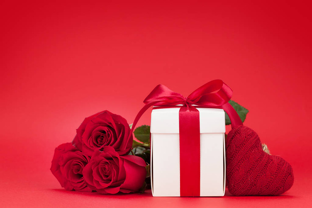 Dia dos Namorados cartão de saudação com buquê de flores rosa e caixa de presente sobre fundo vermelho com espaço de cópia para suas saudações
 - Foto, Imagem