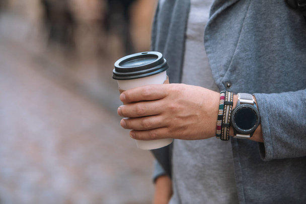χέρι άνδρα κοντά κρατώντας ένα φλιτζάνι καφέ μιας χρήσης - Φωτογραφία, εικόνα