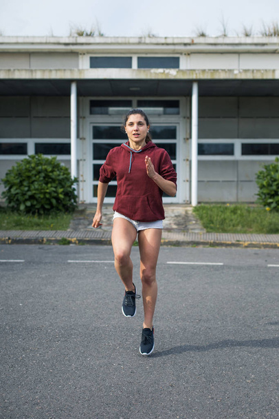 Female athlete running in place. Sporty young woman training on asphalt. - Photo, image