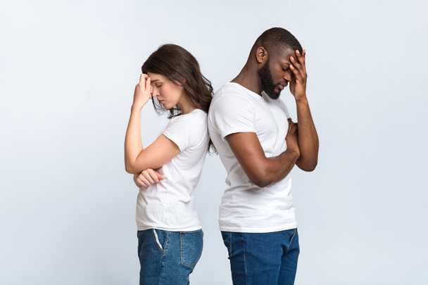 Depressed interracial couple standing back to back after arguing - Fotoğraf, Görsel