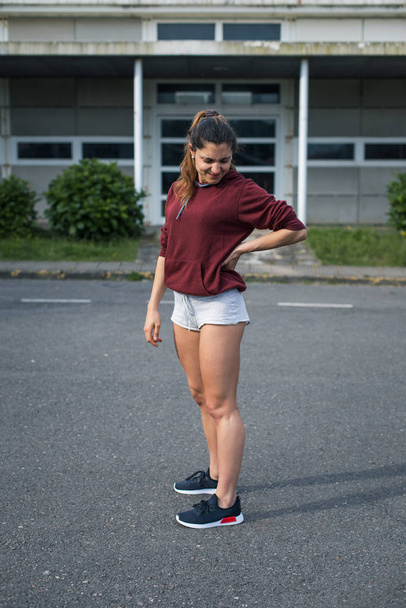 Young female athlete suffering from lower back pain while running on asphalt. - Valokuva, kuva