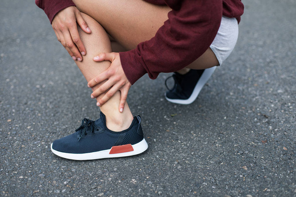 Painful running injury. Detail of runner holding her ankle. Soleus muscle tendonitis. - 写真・画像