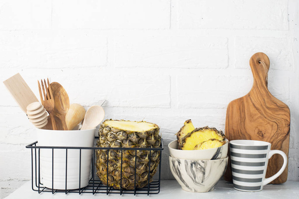 Kitchen shelf lifestyle white background with fresh lemons, pineapple, kitchen tools, appliances, chopping boards, storage baskets. Eco-friendly life. Home style, minimalism, healthy eating - Фото, зображення