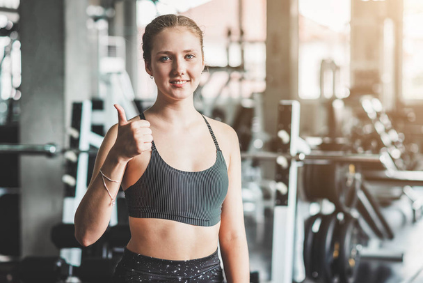 Mujer sana mostrando el pulgar hacia arriba signo en el gimnasio de fitness
  - Foto, Imagen