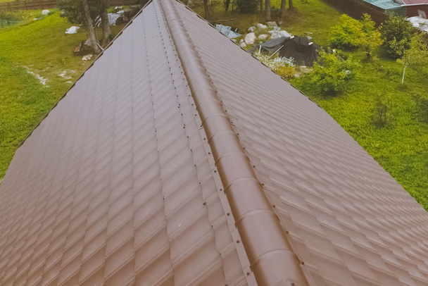 Baldosas de metal marrón en el techo de la casa. Techo de metal corrugado
 - Foto, imagen