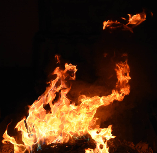 Φωτιά με κίτρινες και πορτοκαλί φλόγες σε μαύρο φόντο - Φωτογραφία, εικόνα