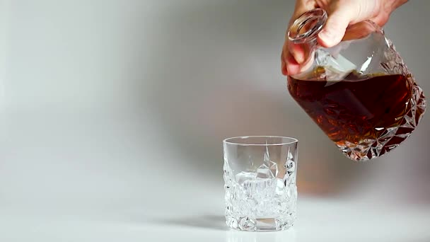 Court métrage montrant du whisky versé dans un verre à gobelet avec de la glace sur fond blanc. Au ralenti. Beaux milieux. Concept d'alcool
. - Séquence, vidéo