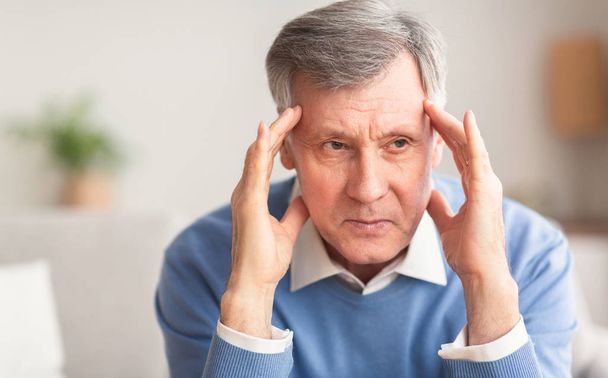 Elderly Man Having Headache Touching Temples Sitting On Couch - Photo, Image