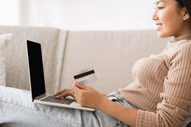 Płatność online. Dziewczyna posiadająca kartę kredytową za pomocą laptopa - Zdjęcie, obraz