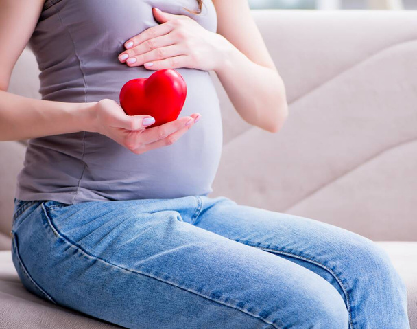 Donna incinta con una pancia pancia seduta su un divano a casa - Foto, immagini