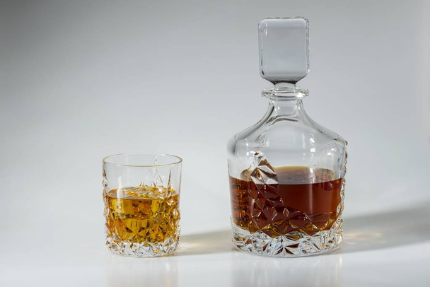 Hermosa vista decantador de whisky y vaso de whisky con hielo sobre fondo azul. Hermosos fondos. Concepto de alcohol
. - Foto, Imagen