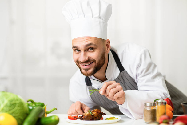 Chef άνθρωπος μαγείρεμα κοτόπουλο διακόσμηση πιάτων με βότανα στην κουζίνα - Φωτογραφία, εικόνα