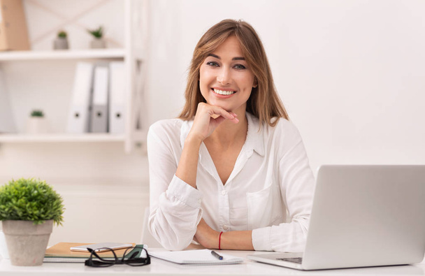 Happy Businessswoman sedí na notebooku s úsměvem v moderní kanceláři - Fotografie, Obrázek