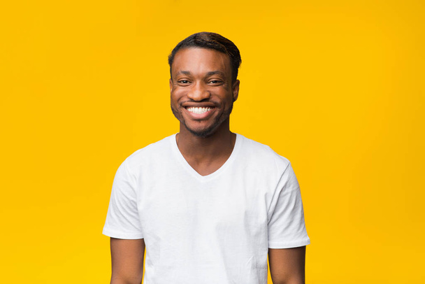 zwart guy in wit t-shirt glimlachen naar camera, studio schot - Foto, afbeelding