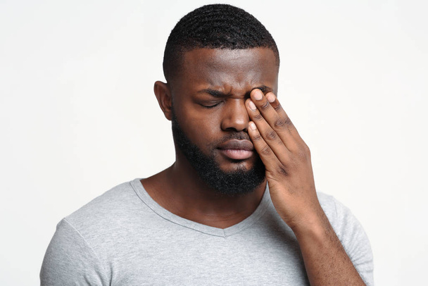 Surullinen musta kaveri koskettaa hänen silmäänsä, kärsii conjuctivitis
 - Valokuva, kuva