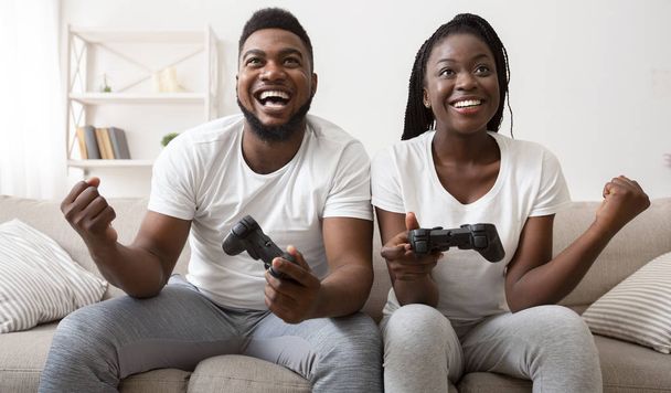 Joyful afro couple celebrating victory in video game - Foto, immagini