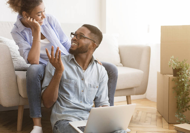 Fekete férj és feleség beszél Laptop számítógép segítségével ül a házban - Fotó, kép