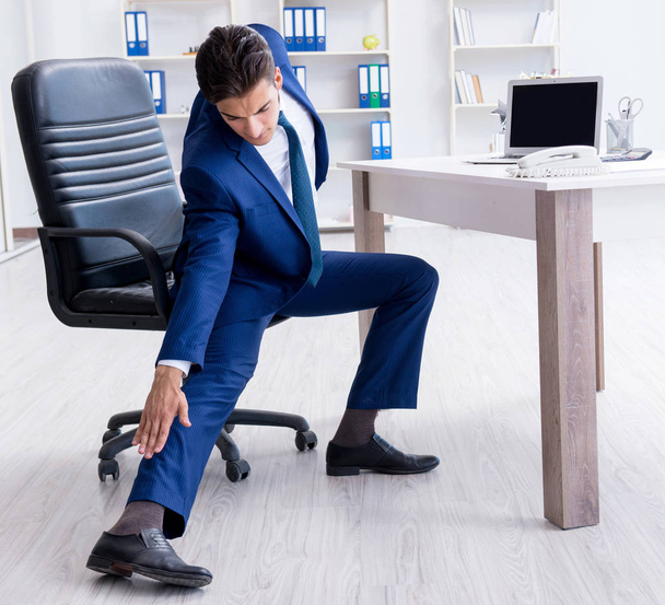 Giovane uomo d'affari che fa sport stretching sul posto di lavoro - Foto, immagini